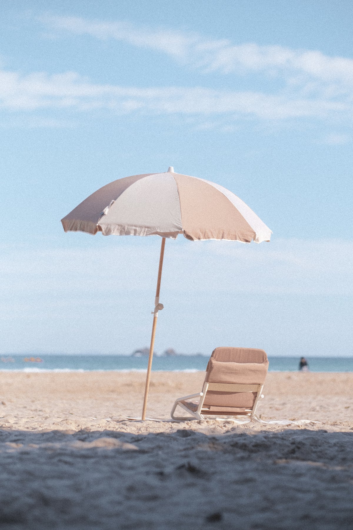 Husk Splice Beach Umbrella and matching Beach Chair viewed across shaded sand