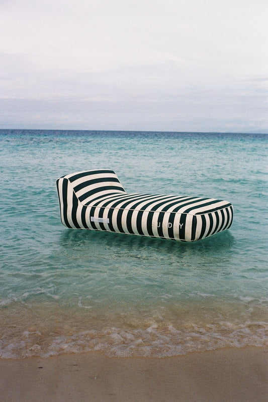 Striped inflatable lounger floating in clear water near the beach