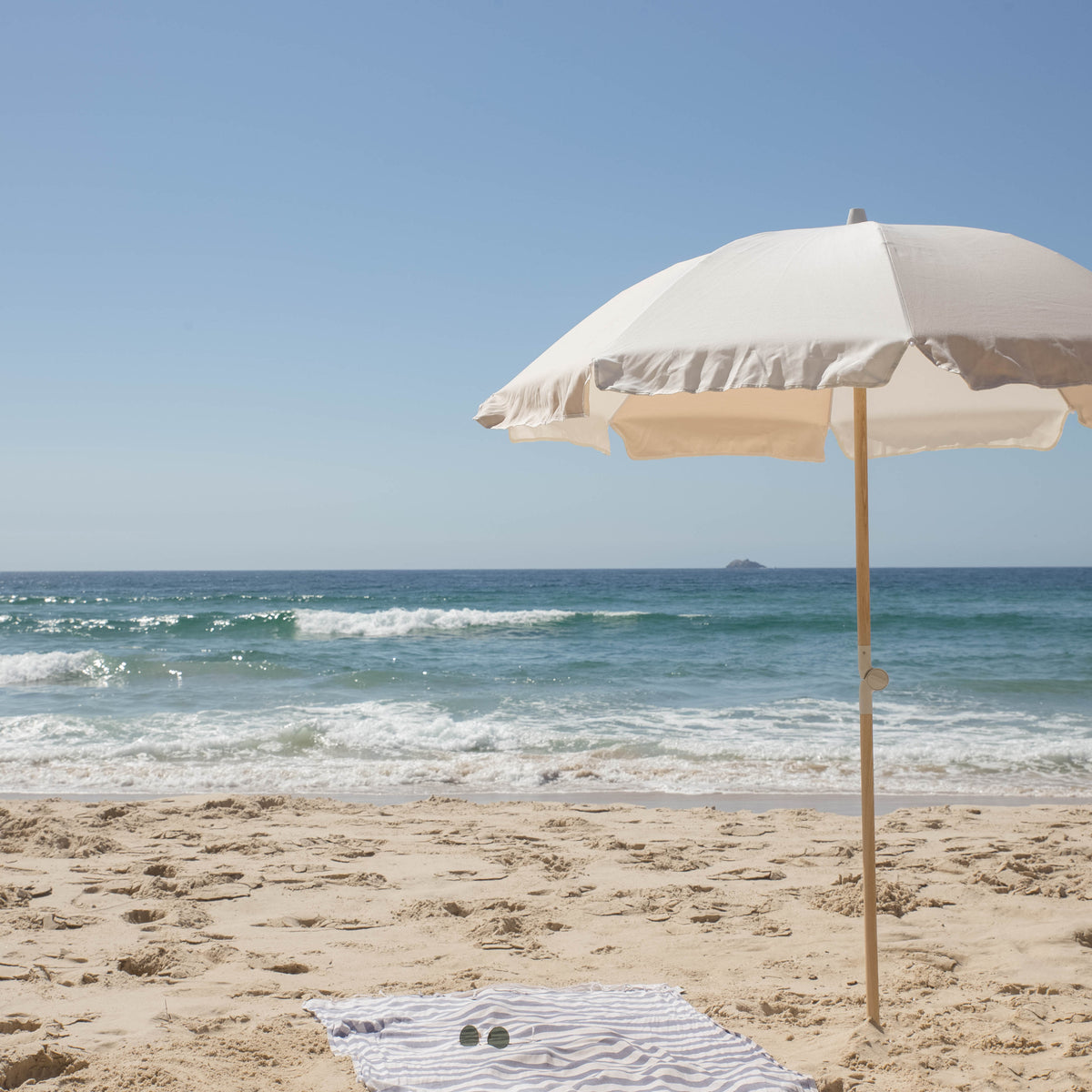 Dunes Splice Beach Umbrella and striped towel on a sandy beach