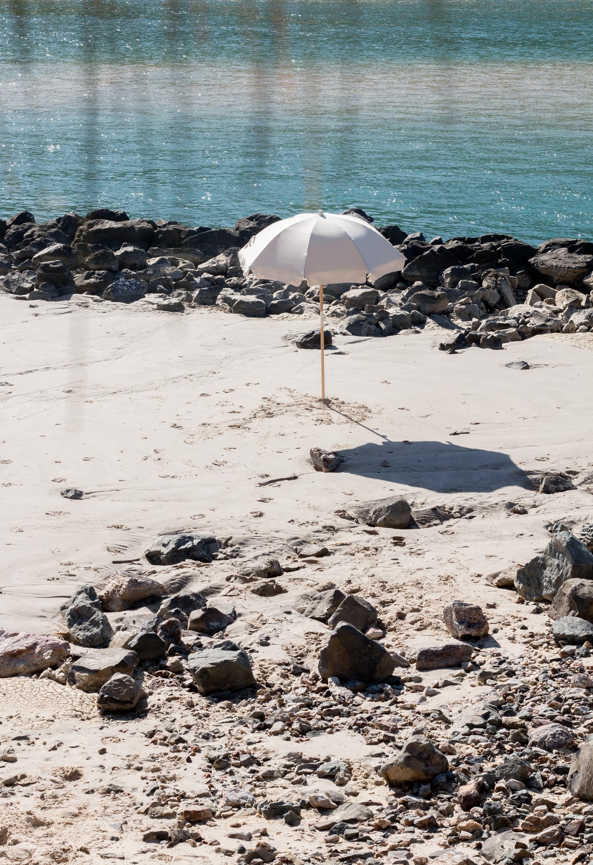 Dunes Splice Beach Umbrella beside clear water and coastal rocks