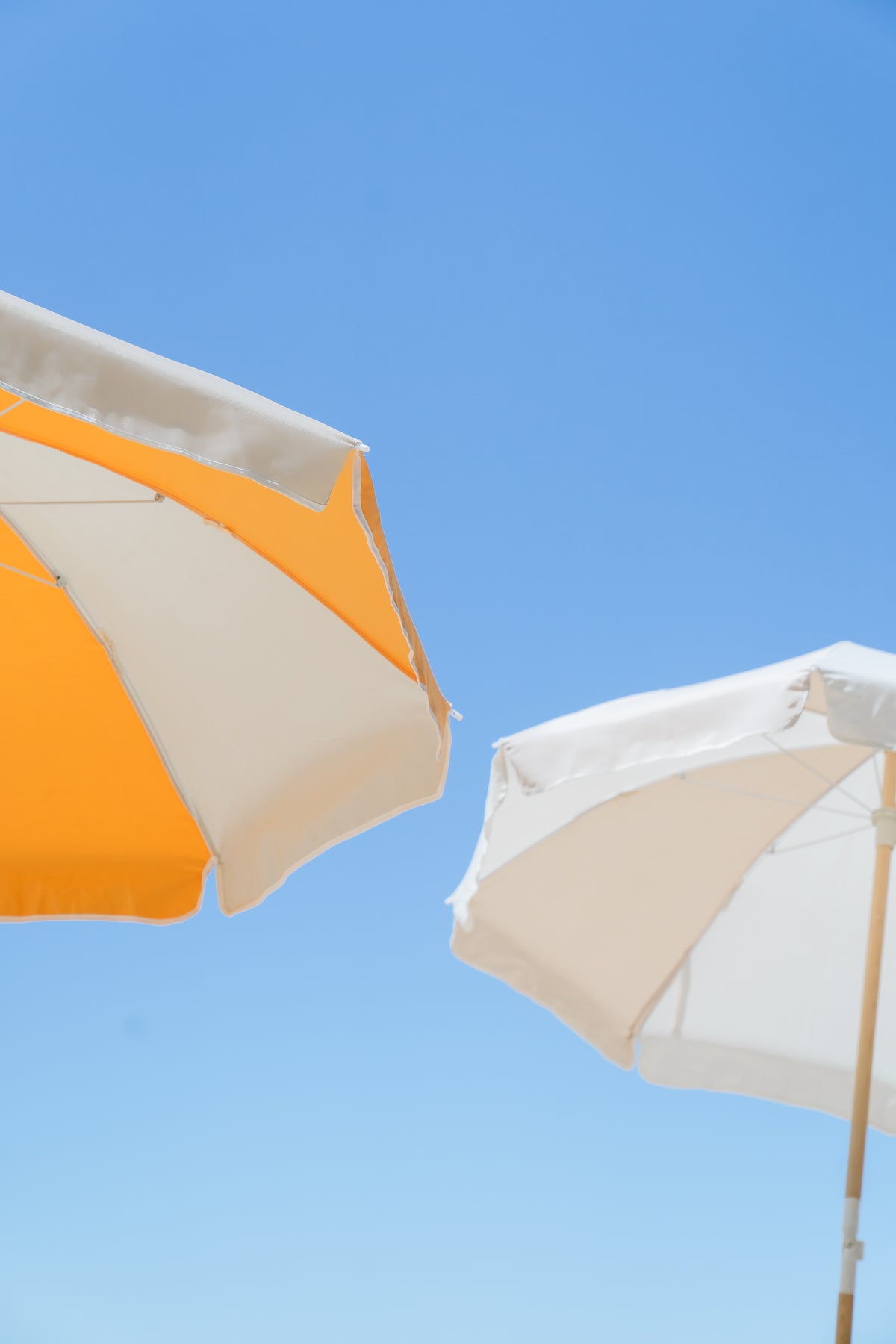 Golden and Dunes Splice Beach Umbrella canopies against a clear blue sky