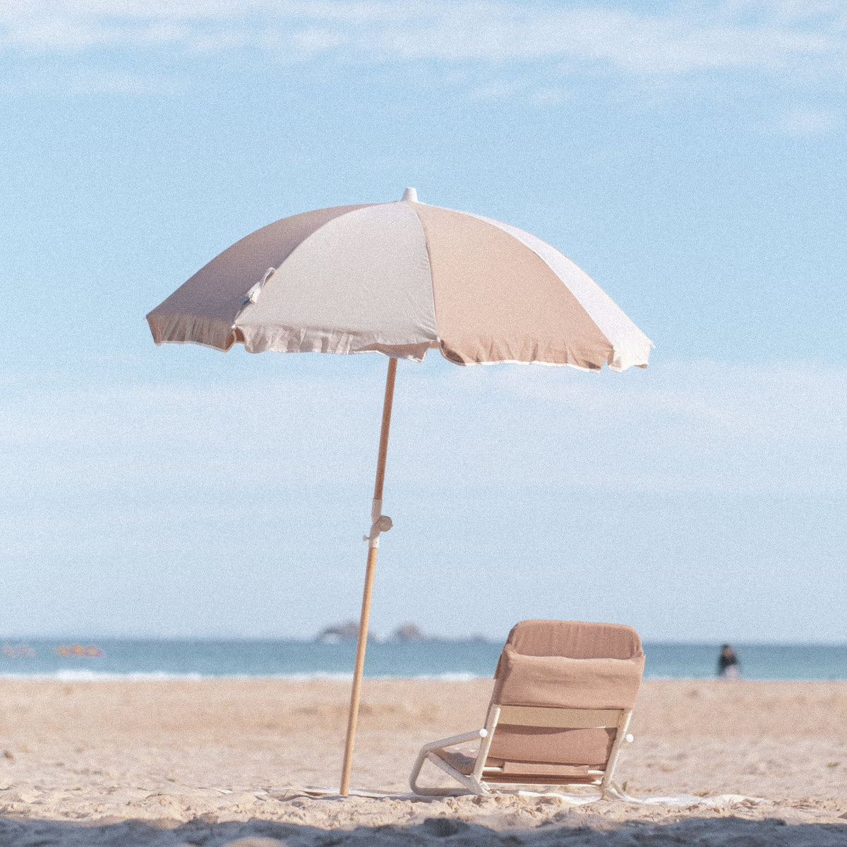 Husk Splice Beach Umbrella and matching Beach Chair viewed across shaded sand