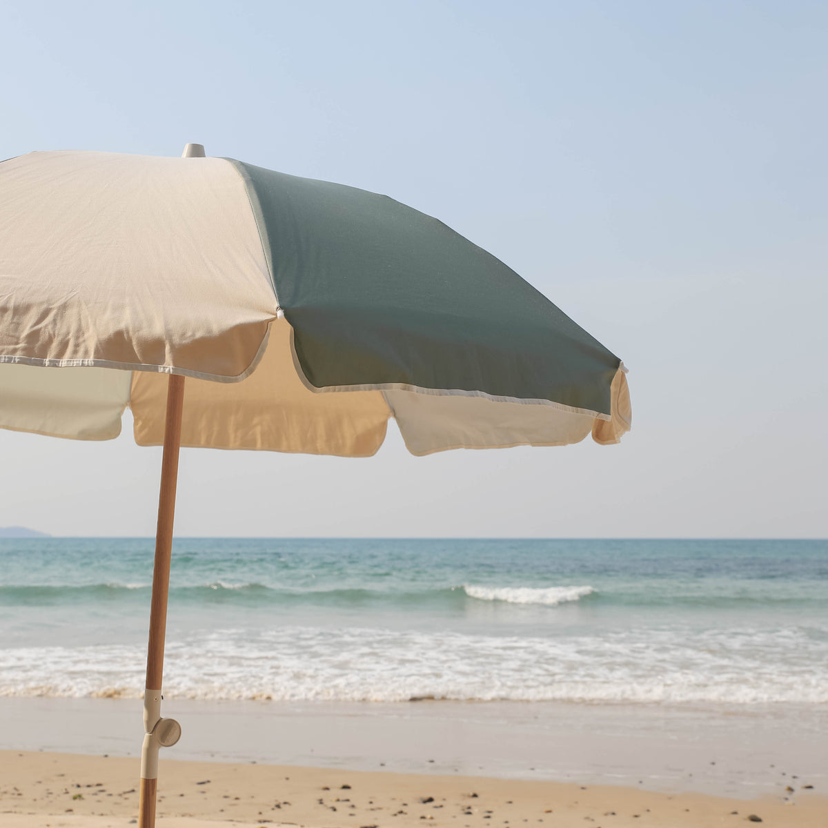 Tallow Splice Beach Umbrella canopy with green and off-white panels by the sea