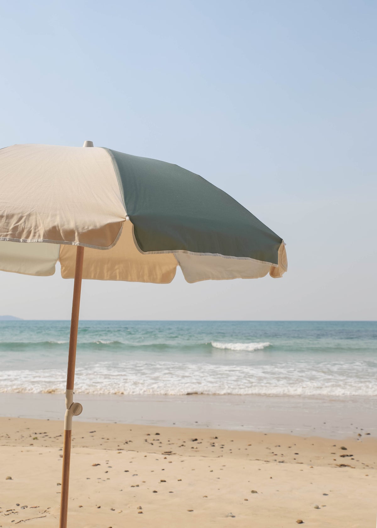 Tallow Splice Beach Umbrella canopy with green and off-white panels by the sea