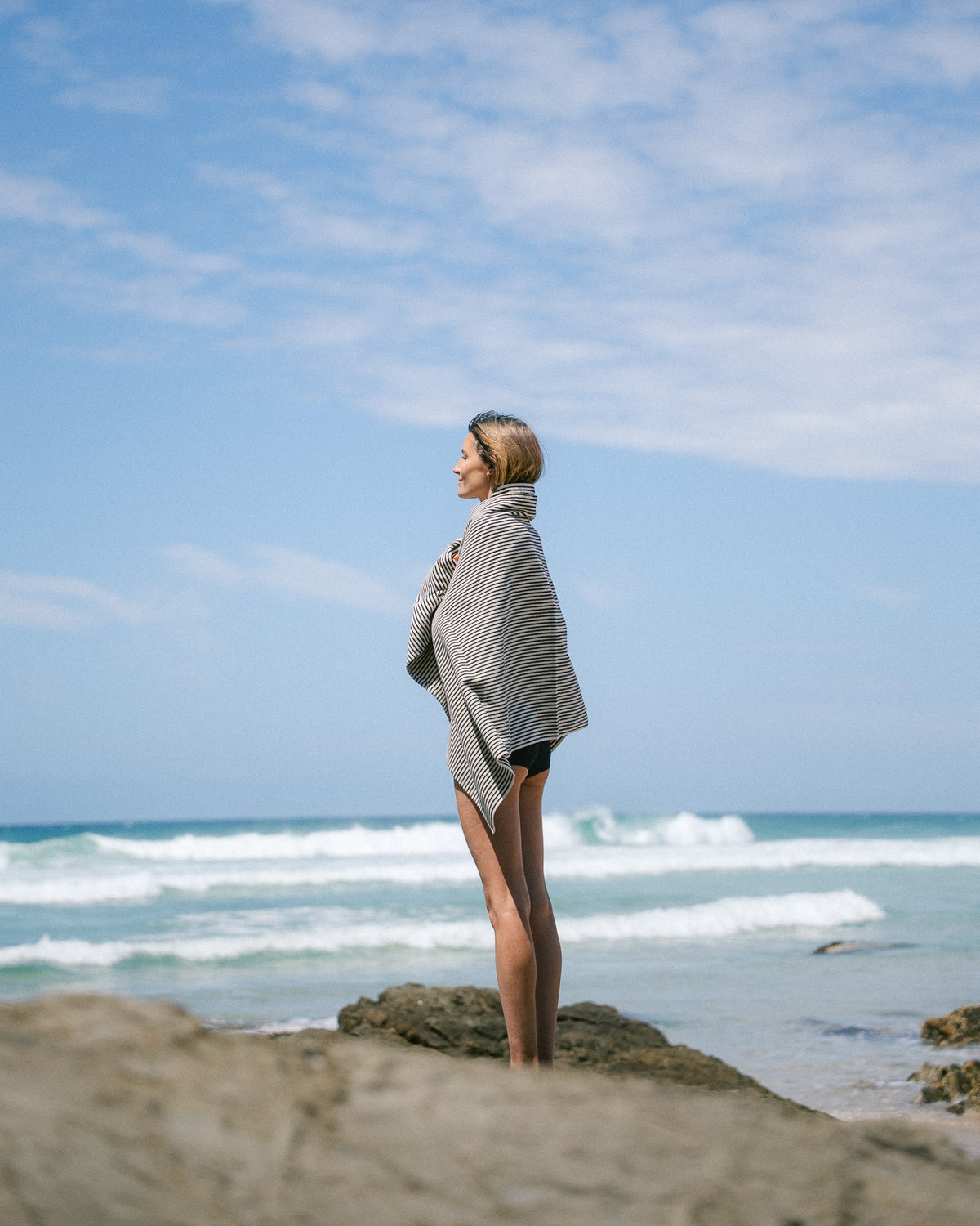 Side view of a model wrapped in a Black striped beach towel.